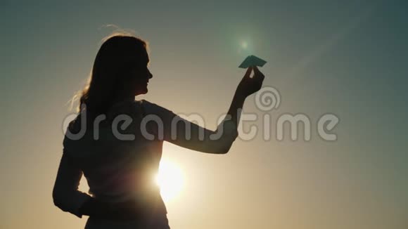 一位中年妇女正在日落时玩纸飞机梦想和童年概念视频的预览图