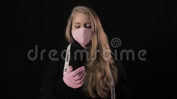 带着白色胶带的女孩Covid19脱下她的粉红色手套和粉红色的医疗面具开始咳嗽孤立于黑色视频的预览图