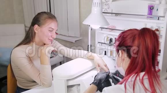 在美容院带手套的女性美甲师在涂胶前先给顾客做一五金美甲视频的预览图