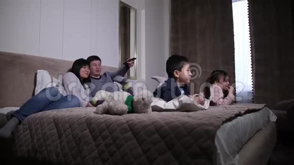 有孩子在床上看电视的快乐亚洲家庭视频的预览图
