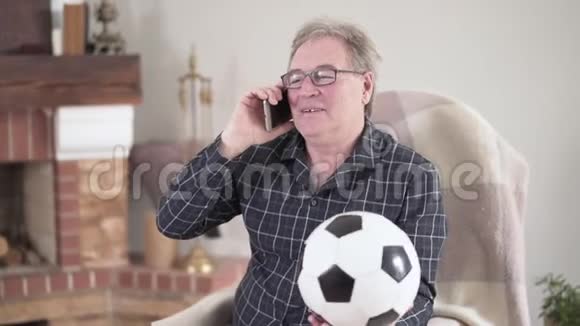 正面的老年白发男子在电话中交谈手持足球的肖像高加索族退休人员视频的预览图