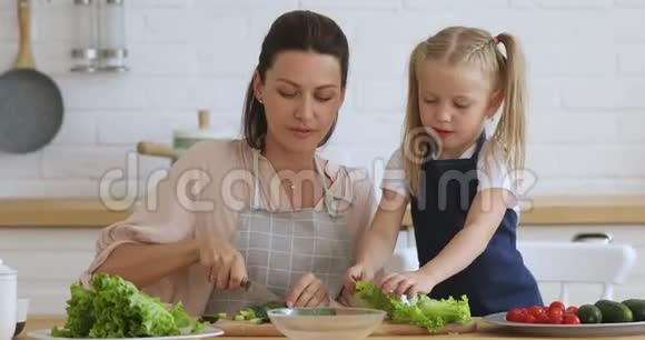 快乐的30多岁的女人教小女儿准备健康的素食食品视频的预览图