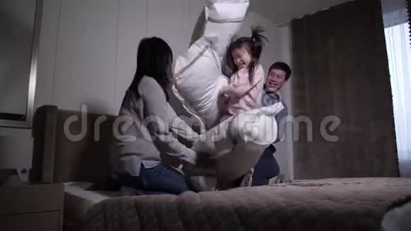 欢乐的亚洲家庭在床上抱着枕头打架视频的预览图