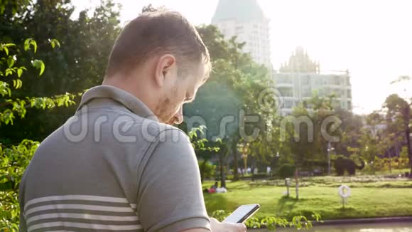 严肃的人在公共公园使用智能手机背景是摩天大楼视频的预览图