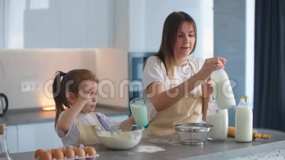 女儿和妈妈一起做饭女人是手把牛奶倒在面团里揉捏妈妈是个小助手视频的预览图