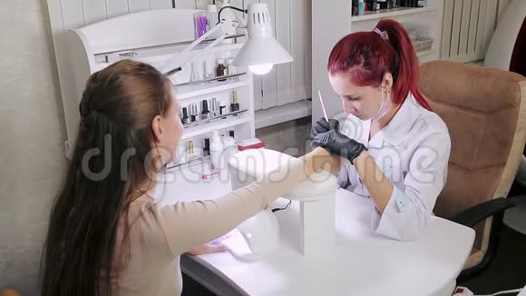美容浴中的美甲医生正在客户指甲上涂胶女孩用紫外线灯晒指甲视频的预览图