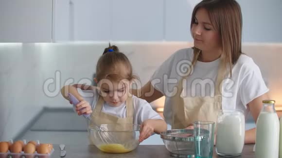 一个学龄前女孩帮妈妈做饭爱的母亲教女儿按家庭做饭视频的预览图