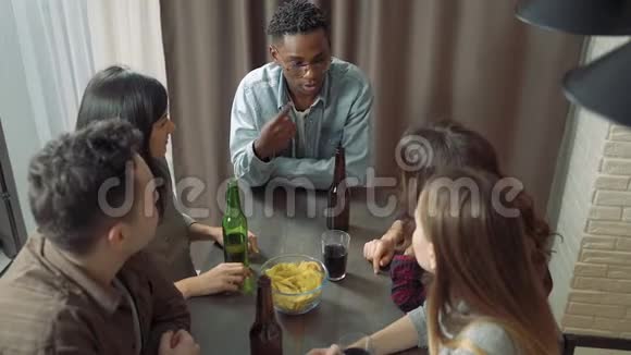多民族的朋友在酒吧或家里谈笑和喝啤酒视频的预览图