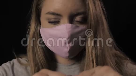 穿着粉红色面具和蓝色眼睛的女孩拿着一条带铭文的带子上面写着Covid19保健和医疗理念关门视频的预览图