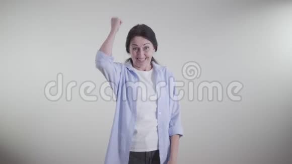 兴奋的高加索女人做胜利的手势在白色的背景上旋转和跳舞成年深色头发的肖像视频的预览图