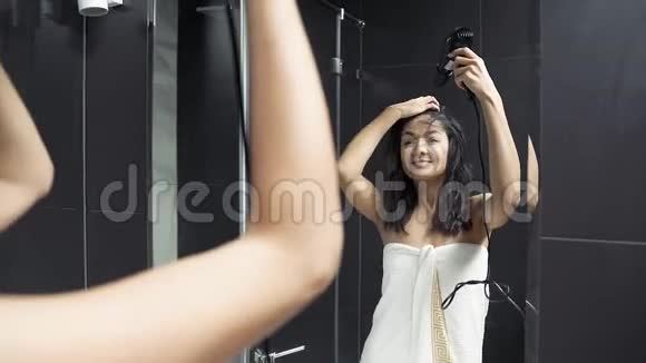 带毛巾干头发的年轻黑发女子浴室配有吹风机视频的预览图