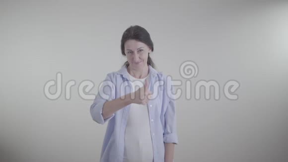 成年深色头发的女人伸出大拇指摇着头表示同意微笑的白种人女士的肖像视频的预览图