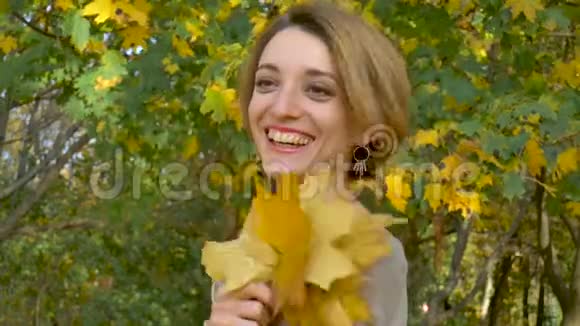 一位情感迷人的年轻女子她的短发和米色连衣裙上面挂着一束秋叶视频的预览图