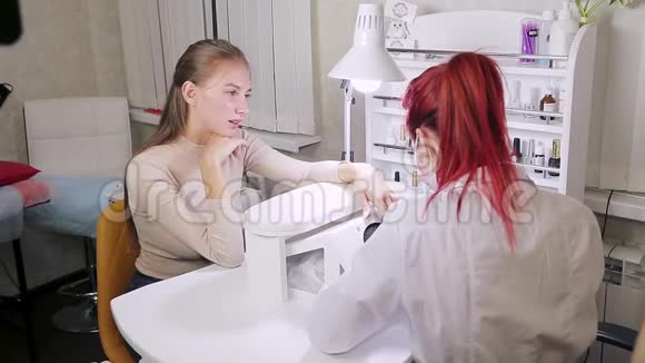 在美容院带手套的女性美甲师在涂胶前对客户做硬件美甲视频的预览图