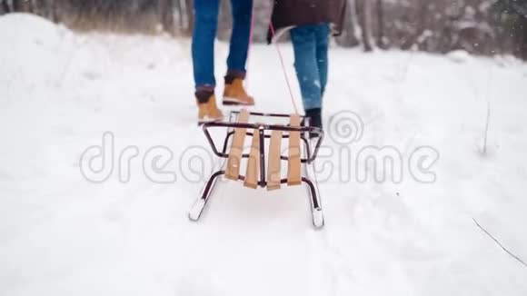 在下雪的冬天可爱的两只脚走路拉雪橇的背面景色一个有女朋友的男人去滑雪女人要走了视频的预览图