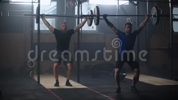 两名运动男运动员用杠铃做操慢动作两个强壮的男人一起举重视频的预览图
