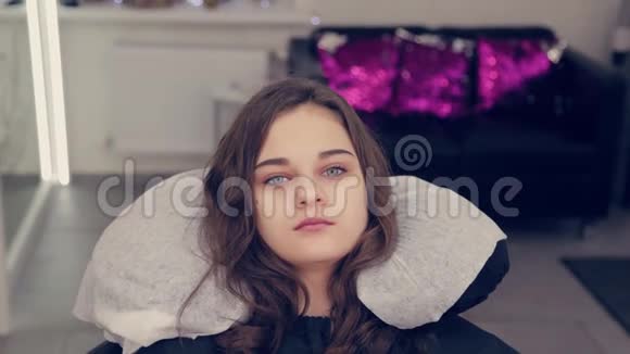 年轻的女孩在美容院的椅子上视频的预览图