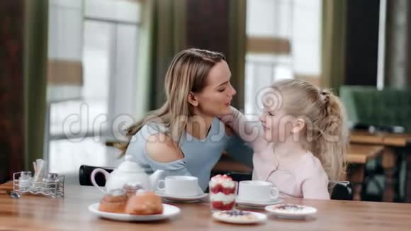 快乐的女人拥抱女婴有最好的感觉坐在桌子旁4K红色相机拍摄视频的预览图