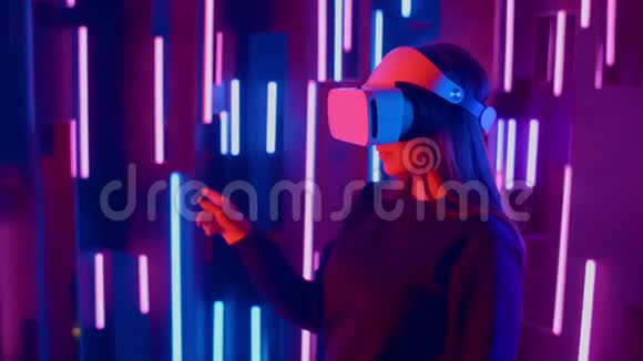 年轻女子在霓虹灯中把VR耳机放在观众身上视频的预览图