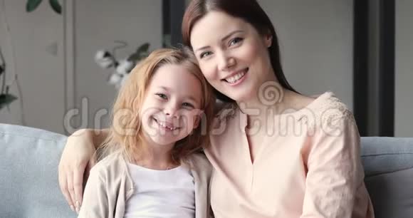 多情的年轻母亲和小女儿一起看着镜头视频的预览图