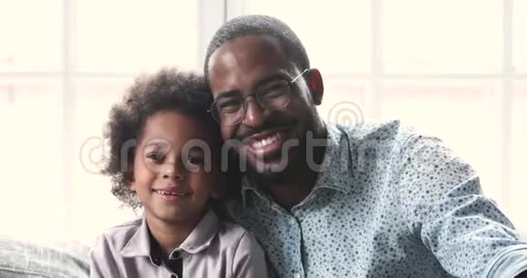 开朗的非洲父亲和小孩儿子看着摄像机视频的预览图