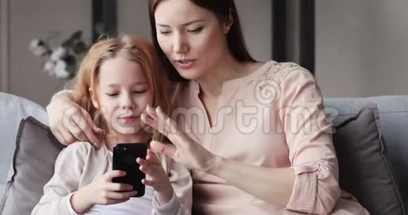 可爱的女儿和妈妈玩智能手机视频的预览图