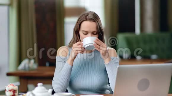 年轻的金发女郎在舒适的咖啡馆里喝茶中型摄影机视频的预览图