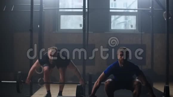 两个强壮的男人一起在健身房做举重训练中档慢动作平底锅男子健身房锻炼视频的预览图