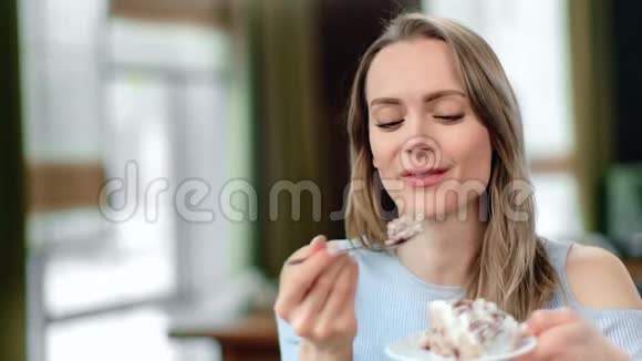 闭着脸可爱的女人吃开胃的蛋糕用勺子感觉愉快4k龙红相机视频的预览图