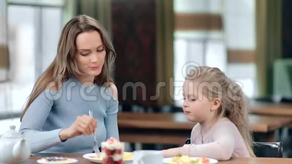 关爱的年轻母亲用叉子喂养可爱的女婴中型摄影机视频的预览图