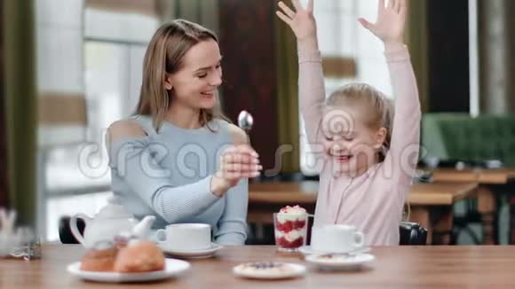 有趣的女孩吃着开胃的奶油甜点在咖啡馆享受美味4K红色相机拍摄视频的预览图