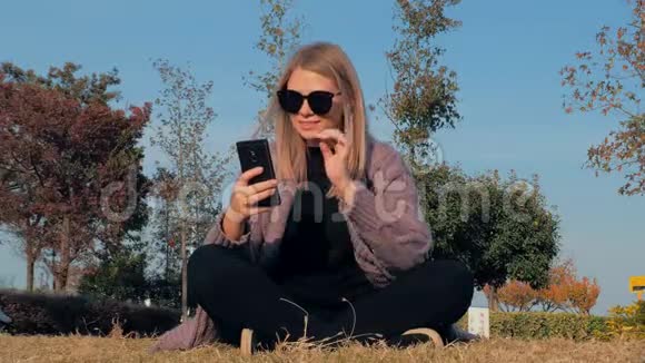 年轻迷人的金发女郎坐在莲花的位置在公园户外自拍视频的预览图