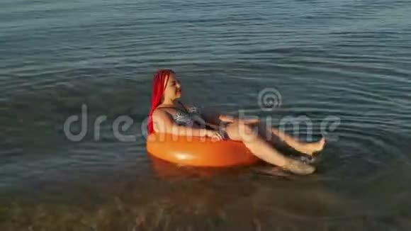 一个穿着泳衣穿着红发的女人在游泳圈晒太阳视频的预览图