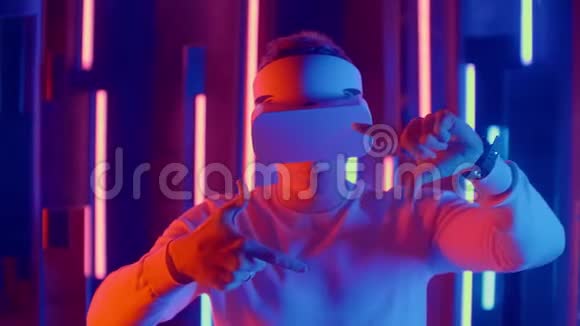 无脸男子戴VR耳机在黑暗空间与霓虹灯用户头转向一边看虚拟视频的预览图