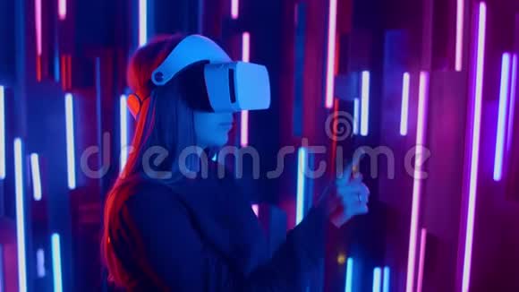 女人戴着VR耳机从一边到另一边快速倾斜同时在黑暗的空间里玩照亮了霓虹灯视频的预览图