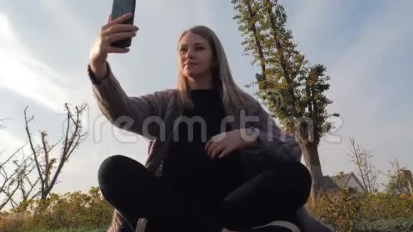 年轻迷人的金发女郎坐在莲花的位置在公园户外自拍视频的预览图