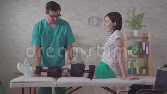男性理疗师在受伤后帮助双膝关节矫形器视频的预览图