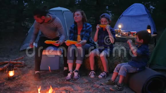 家庭晚餐靠近大自然的火焰家庭吃盐玉米旅行野营妈妈爸爸和儿子吃新鲜的黄色视频的预览图
