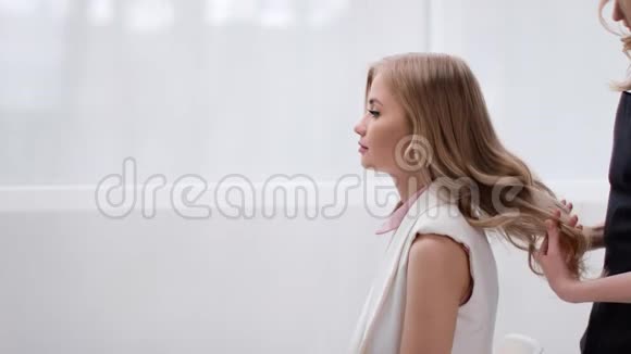 女造型师漫步年轻模特卷曲的金发中型摄影机视频的预览图