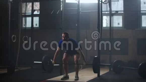 年轻运动员举起沉重的杠铃健康肌肉发达一个强壮的男子在健身房缓慢地做杠铃抓举练习视频的预览图