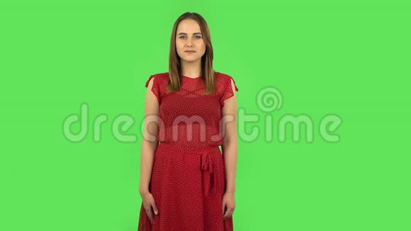 穿着红色衣服的温柔女孩被诱惑地微笑并通过摇动食指威胁手势绿色屏幕视频的预览图