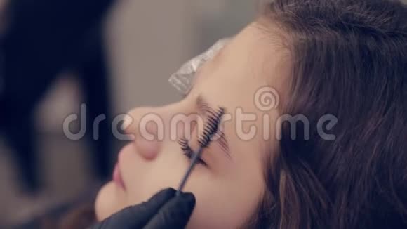 在一家美容院专业的眉毛大师将胶卷从眉毛上取下并去除眉毛上的液体视频的预览图