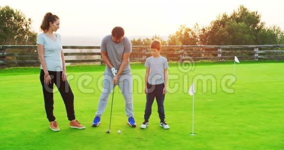 快乐的父母和年幼的儿子一起享受和高尔夫俱乐部一起练习的时光视频的预览图