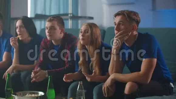 情绪球迷在电视上兴奋地看足球比赛然后高兴地坐在沙发上的胜利视频的预览图