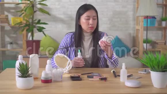 一位亚洲年轻女子精心挑选化妆品的肖像视频的预览图