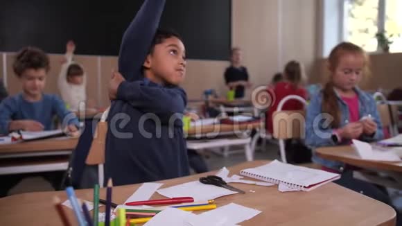 活跃可爱的男孩自信地在课堂上举手视频的预览图