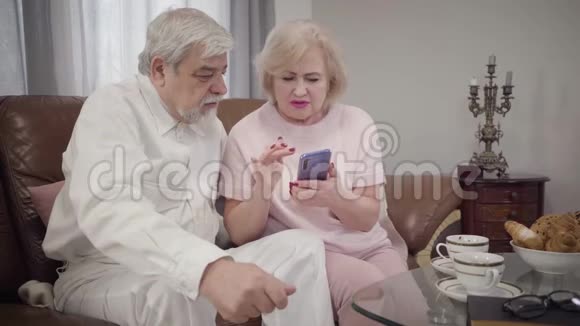 现代白人女性教她优雅的丈夫使用智能手机智能成熟女性退休人员视频的预览图