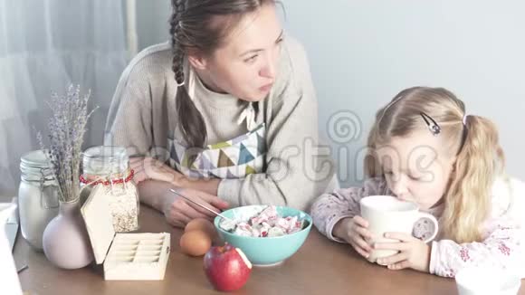 妈妈和小女儿坐在厨房的桌子旁宝宝喝牛奶视频的预览图