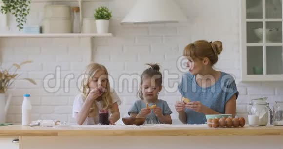 快乐的孩子们和妈妈吃自制的果酱饼干视频的预览图