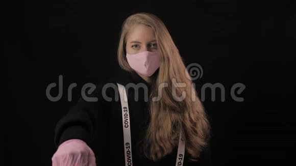 戴着粉红色面具的女孩和一条刻着covid19号的丝带显示了不赞成的姿态孤立于黑色视频的预览图